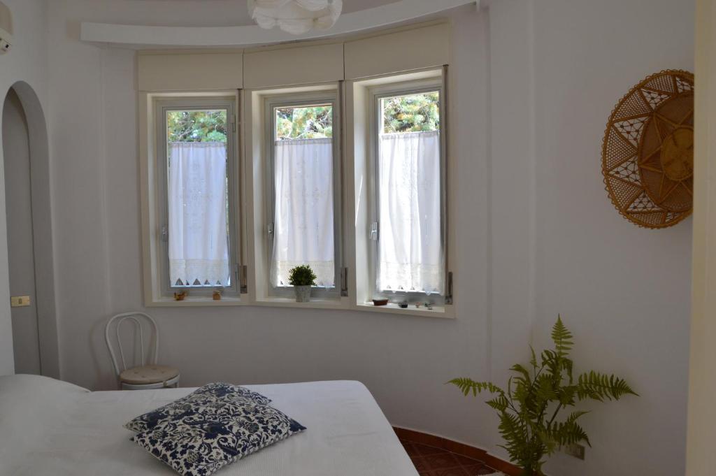 Cette chambre dispose de 3 fenêtres et d'une table avec un oreiller. dans l'établissement Villa Bouganvilla, à Cefalù