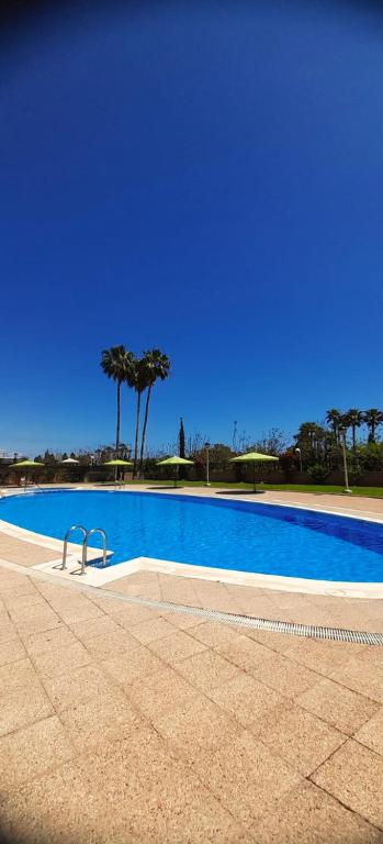 ein großer blauer Pool mit Bäumen im Hintergrund in der Unterkunft Costa Caribe II Nº 1028 in Oropesa del Mar