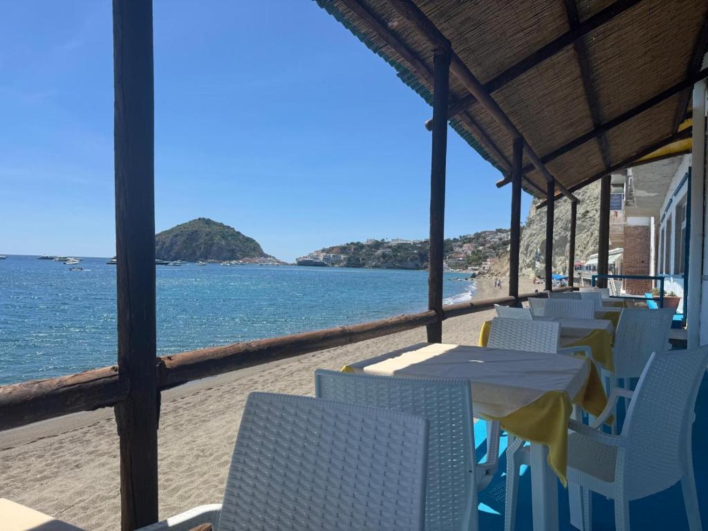 a table and chairs on a beach with the ocean at Hotel Angelino in Ischia