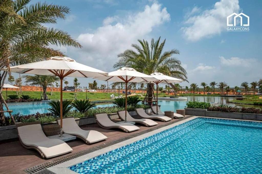a swimming pool with lounge chairs and umbrellas at DCAO Villas Novaworld Phan Thiet in Bình Tú