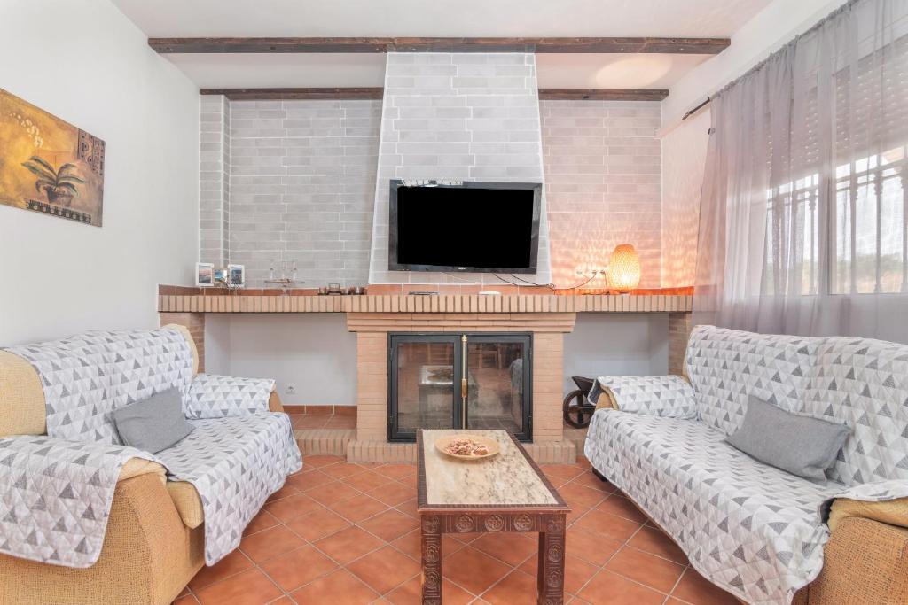 ein Wohnzimmer mit zwei Sofas und einem Kamin in der Unterkunft Casa rural Montemayor in Moguer