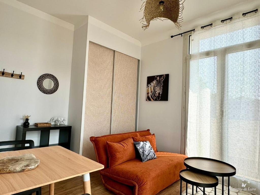 - un salon avec une chaise orange et une table dans l'établissement Appartements Balcony de Loire, à Tours