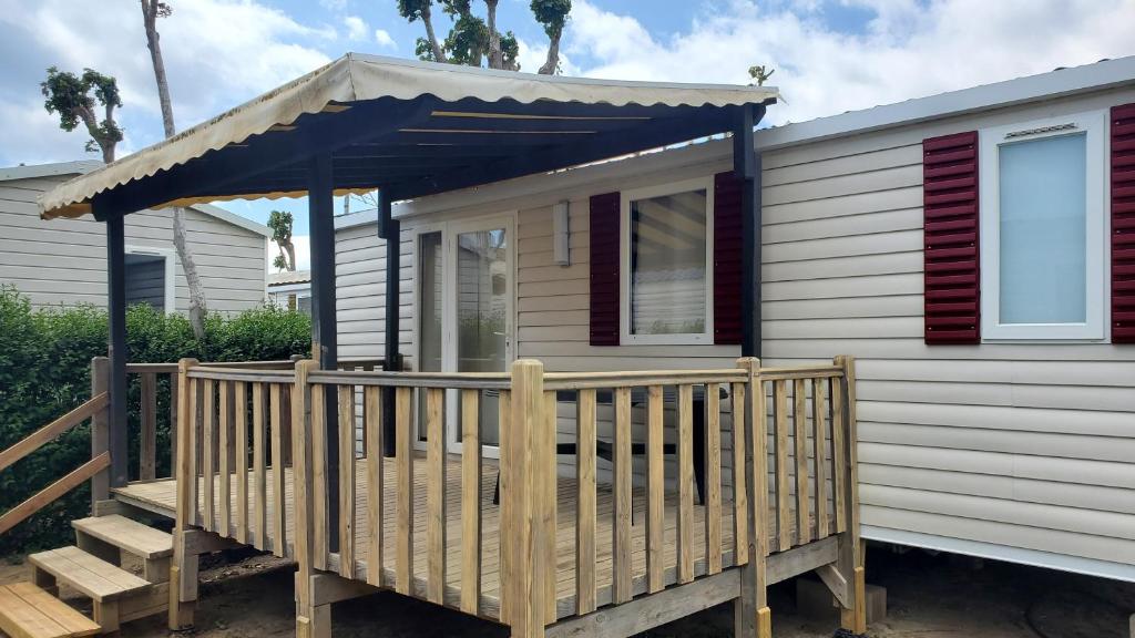 une petite maison avec une véranda et un auvent dans l'établissement Mobilhomelaco34siblu, à Valras-Plage