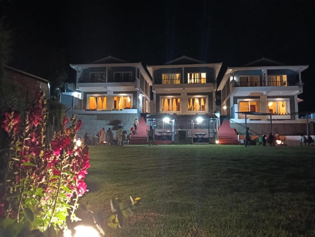 a large building at night with a lawn in front of it at Longwood Resorts in Kotagiri