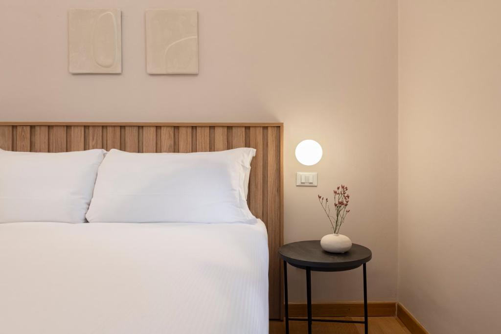a bedroom with a bed and a table with a vase on it at RELSTAY - Assarotti Suites in Genoa