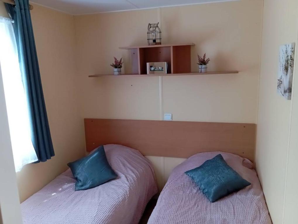 two beds in a room with blue pillows at MOBILHOME 4 places in Sainte-Croix-de-Verdon