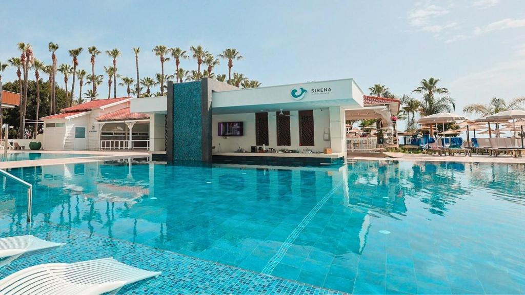 a large swimming pool at a resort with palm trees at Cavo Maris Beach Hotel in Protaras