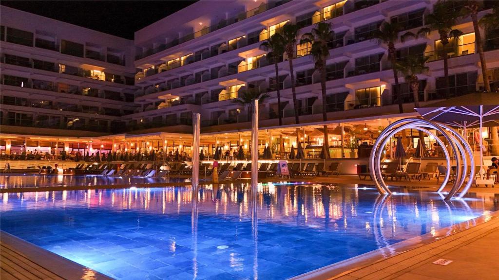 a swimming pool in front of a building at night at Cavo Maris Beach Hotel in Protaras