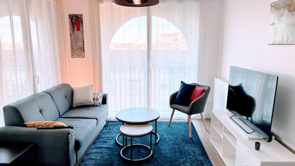 un salon avec un canapé, une télévision et une table dans l'établissement le quai douillet, à Bordeaux