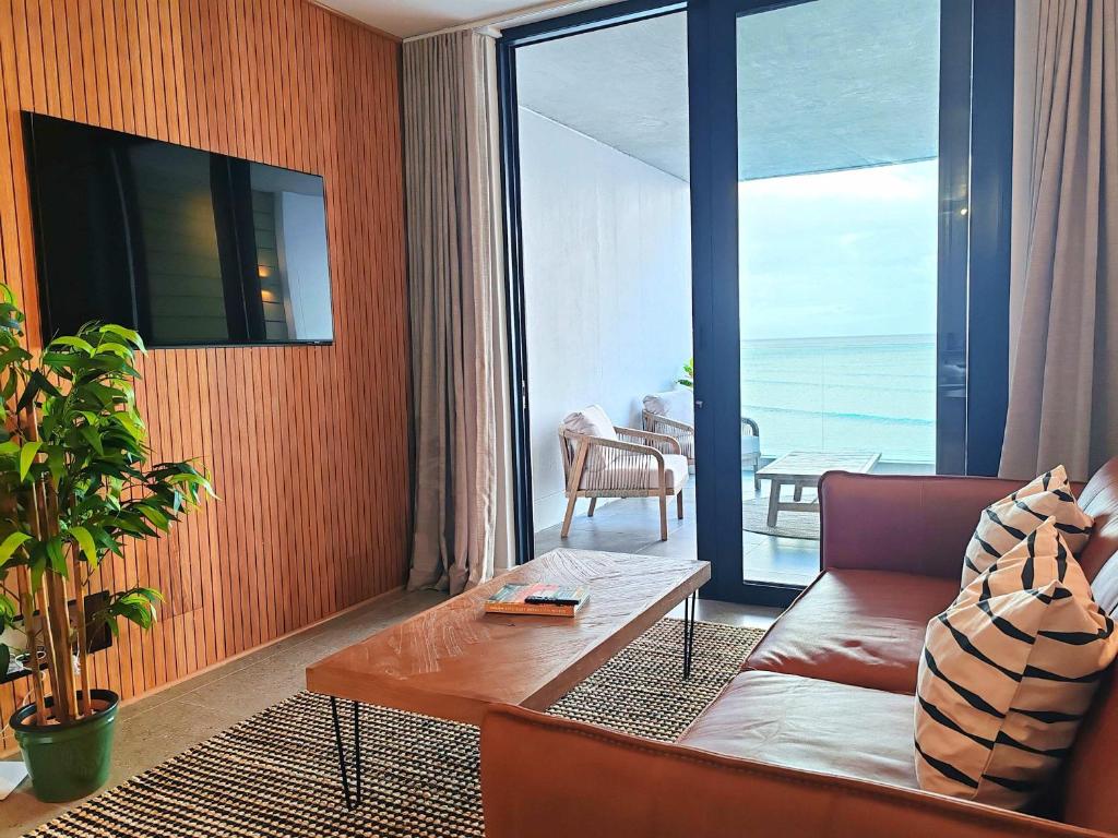 a living room with a couch and a large window at Wavescapes Endless Ocean in Muizenberg