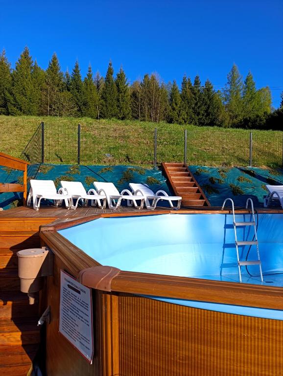a hot tub on a deck with lawn chairs at Czesławka in Zawoja