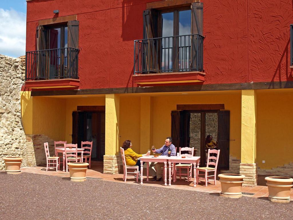 two people sitting at a table in front of a building at Casa Arrieta in Castejón de Valdejasa