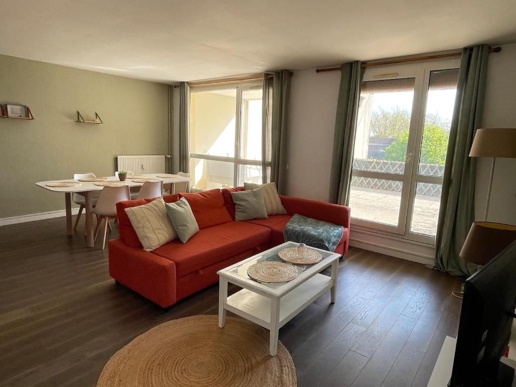 a living room with a red couch and a table at Le Duplex Convivial de Compiègne in Compiègne