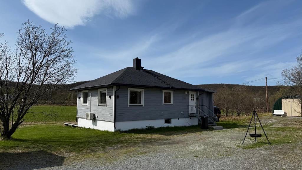 a small house sitting on top of a field at Koselig hus i sentrum av Olderfjord in Russenes