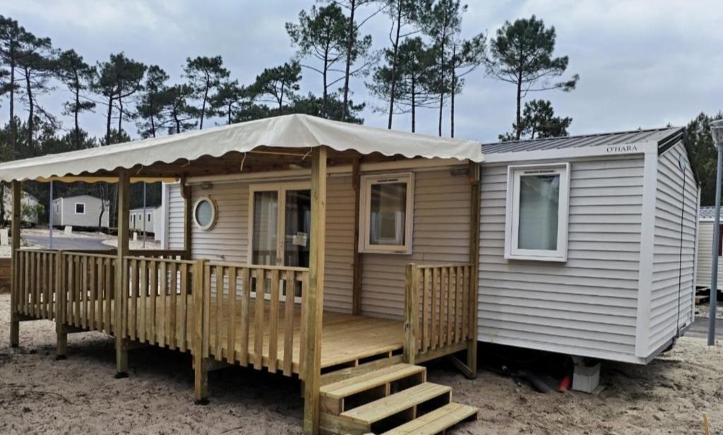 une maison en bois avec une véranda et un parasol dans l'établissement Mobil home 6p à Lacanau Océan, à Lacanau