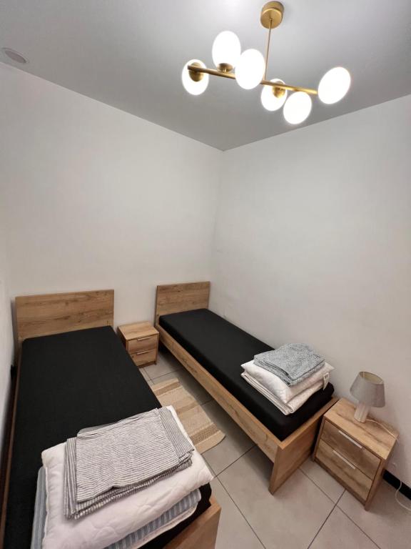 Habitación con 2 camas y lámpara de araña. en Dworskiego 74 Apartament 5, en Przemyśl