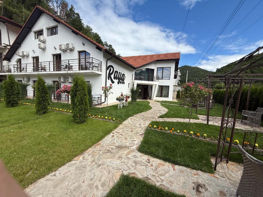 a large white house with a garden in front of it at Pensiunea Raya in Dubova