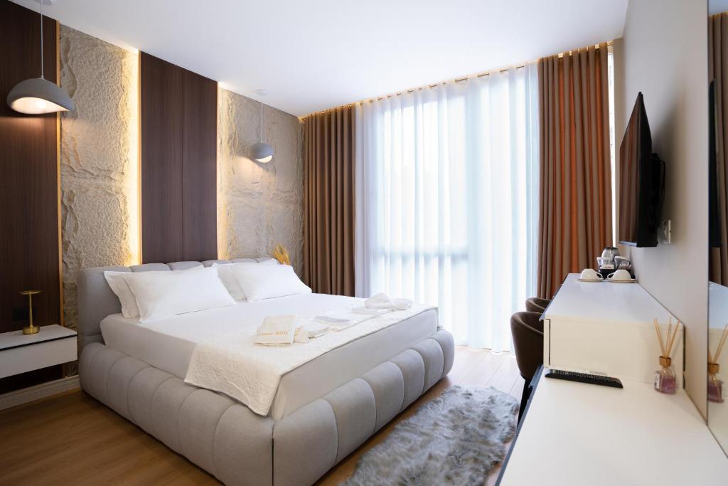 ein Hotelzimmer mit einem weißen Bett und einem Fernseher in der Unterkunft Gamma Hotel Durres - FREE PARKING & SUNBEDS in Durrës