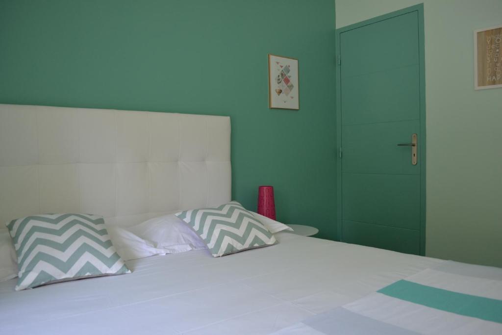 1 dormitorio con cama blanca y puerta verde en Demeure & Dépendance - Chambres d'hôtes depuis 2012, en Tassin-la-Demi-Lune