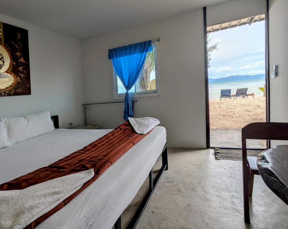 a bedroom with a bed and a window with the beach at Dreamy beachfront bungalow in Baan Tai