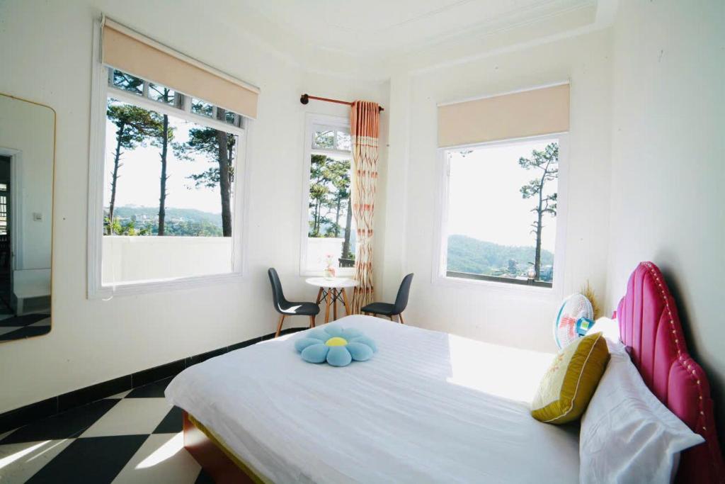 a bedroom with a bed with two chairs and two windows at Moon Villa Da Lat in Ấp Ða Lợi