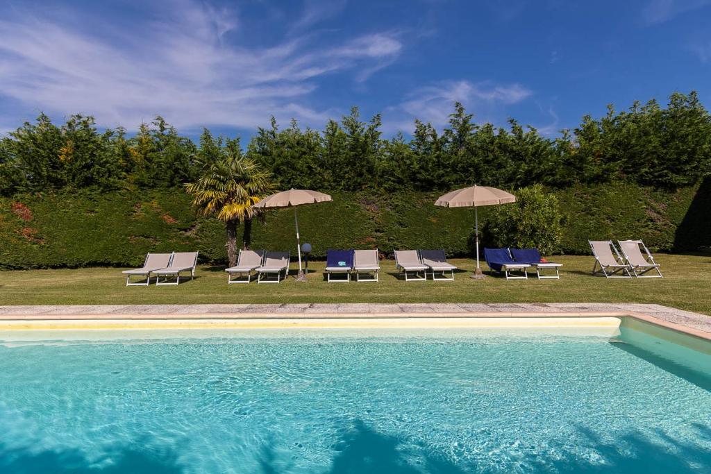 a swimming pool with lounge chairs and umbrellas at B&B Panizzi - San Gimignano in San Gimignano