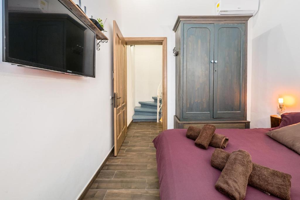 a bedroom with a purple bed and a flat screen tv at Kharmen A 1565s House with Seaviews in Birgu