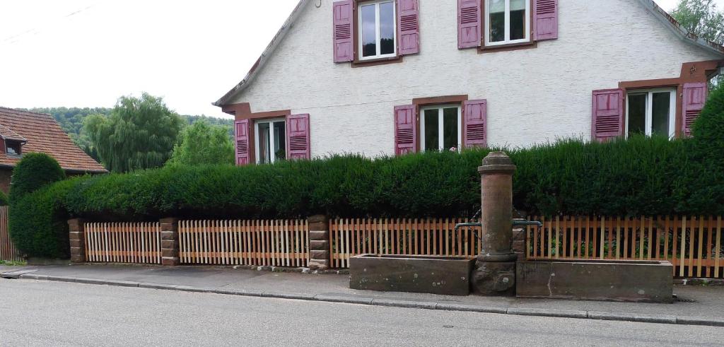 einen Zaun vor einem Haus mit rosa Fensterläden in der Unterkunft Un gîte dans la vallée in Obersteinbach