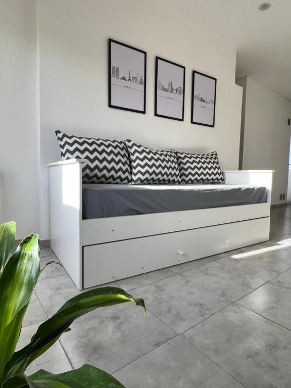 a white bed in a room with three pictures on the wall at FINCA NOVA Apartment 5 in Balcarce