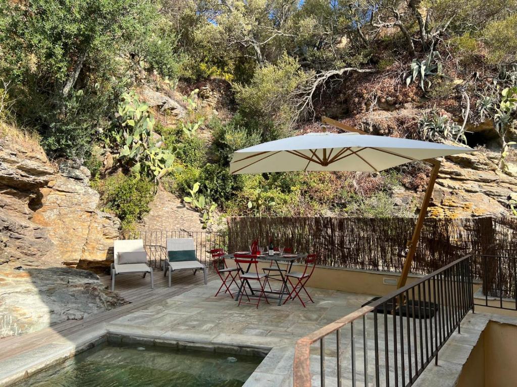 - une terrasse avec une table et un parasol à côté de la piscine dans l'établissement Villa Christelle avec piscine Cap Corse, à Centuri