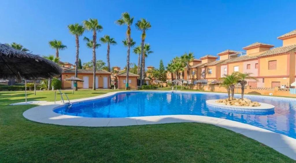 a swimming pool in a villa with palm trees at Inviting house in Lepe with shared pool. in Lepe