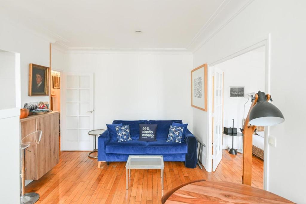 un salon avec un canapé bleu et une table dans l'établissement Appartement lumineux à Paris by Weekome, à Paris