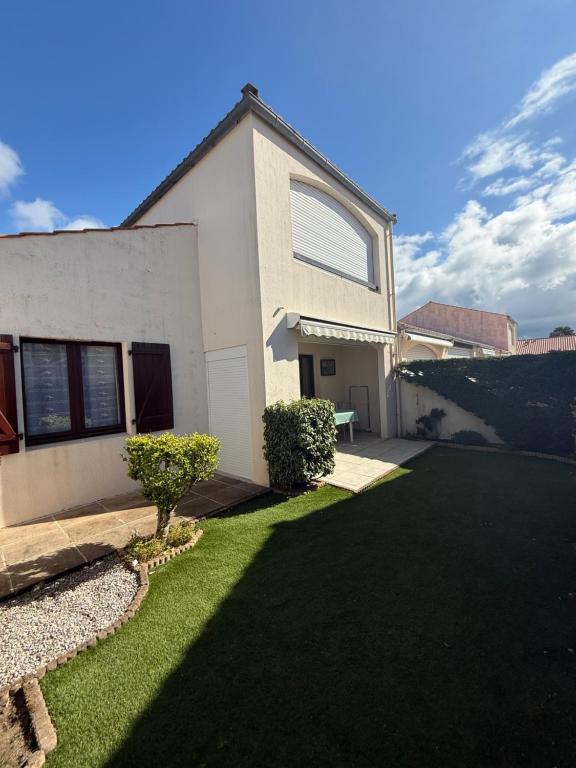 une maison avec une pelouse verte devant elle dans l'établissement Les Courlis, à La Tranche-sur-Mer