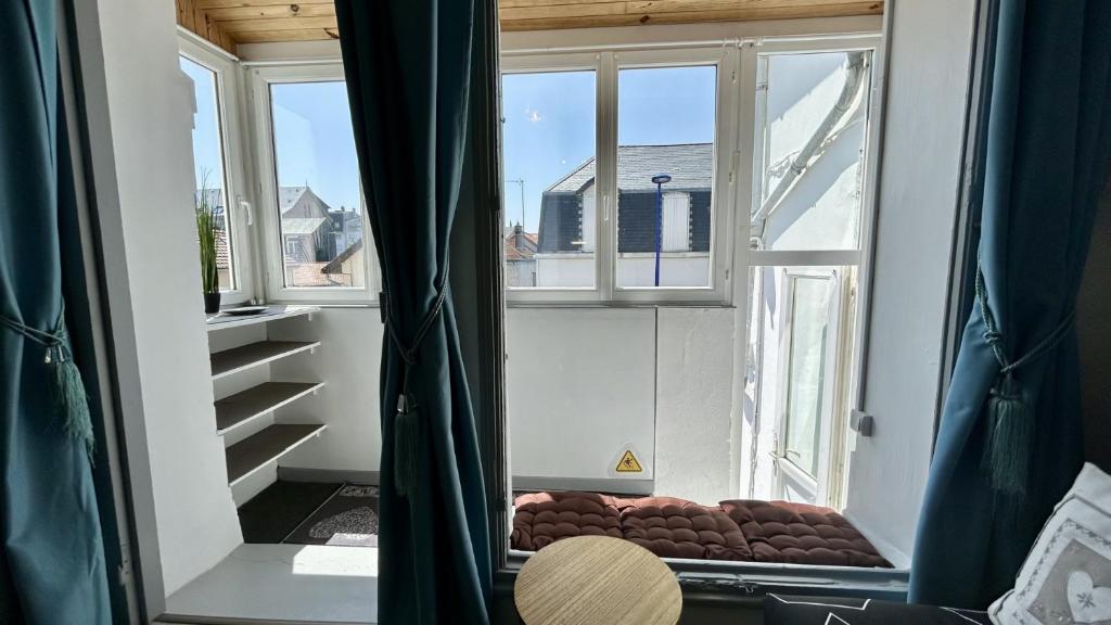 une pièce avec deux fenêtres et un banc devant une fenêtre dans l'établissement Le Petit Cocon, au Crotoy