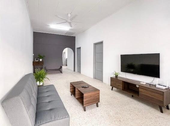 a living room with a couch and a flat screen tv at Pearl Cottage - 2min Drive to Lam Wah Ee Hospital in George Town