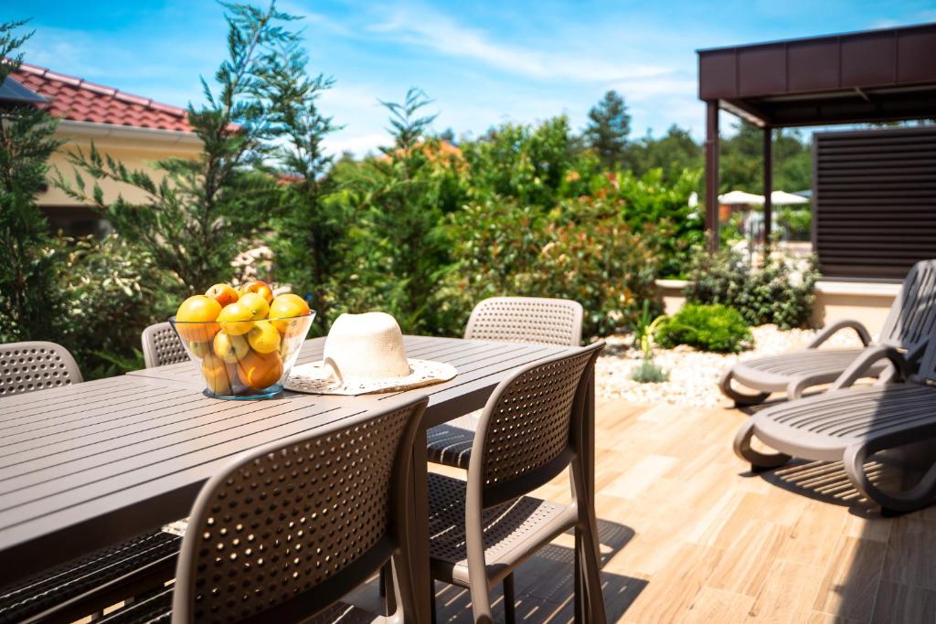 a table with a bowl of fruit on a patio at VSG Resort - Relaxing Apartments, 200m from the Sea, with Pool, Sauna & Jacuzzi in Klimno