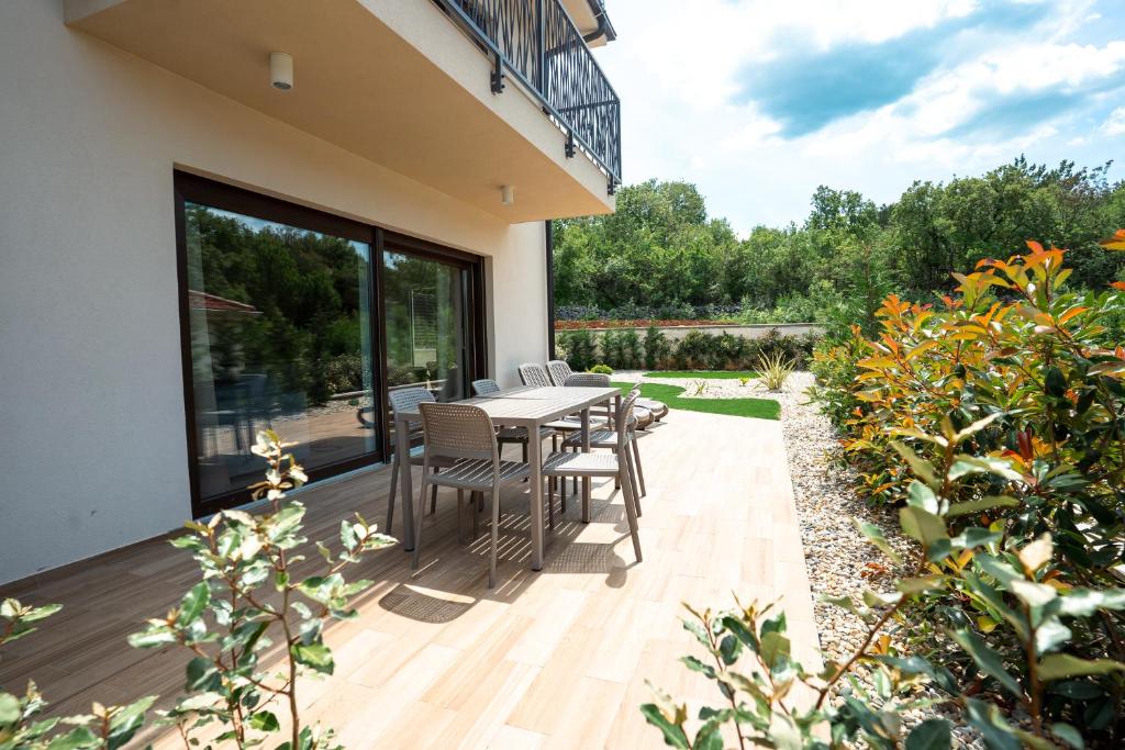 a patio with a table and chairs on a deck at VSG Resort - Relaxing Apartments, 200m from the Sea, with Pool, Sauna & Jacuzzi in Klimno