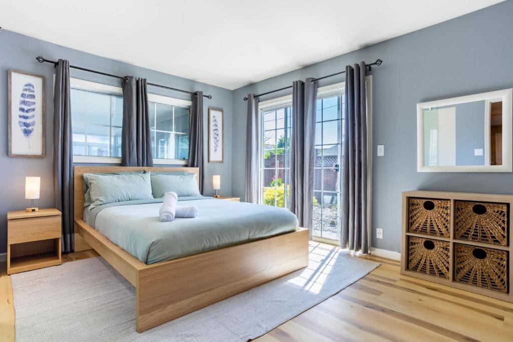 a bedroom with a large bed with blue walls and windows at Wine Waves & Comfort 2BR Bay Area Beauty in Hayward