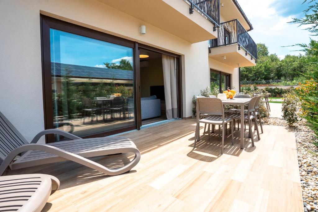 a patio with a table and chairs on a deck at VSG Resort - Relaxing Apartments, 200m from the Sea, with Pool, Sauna & Jacuzzi in Klimno