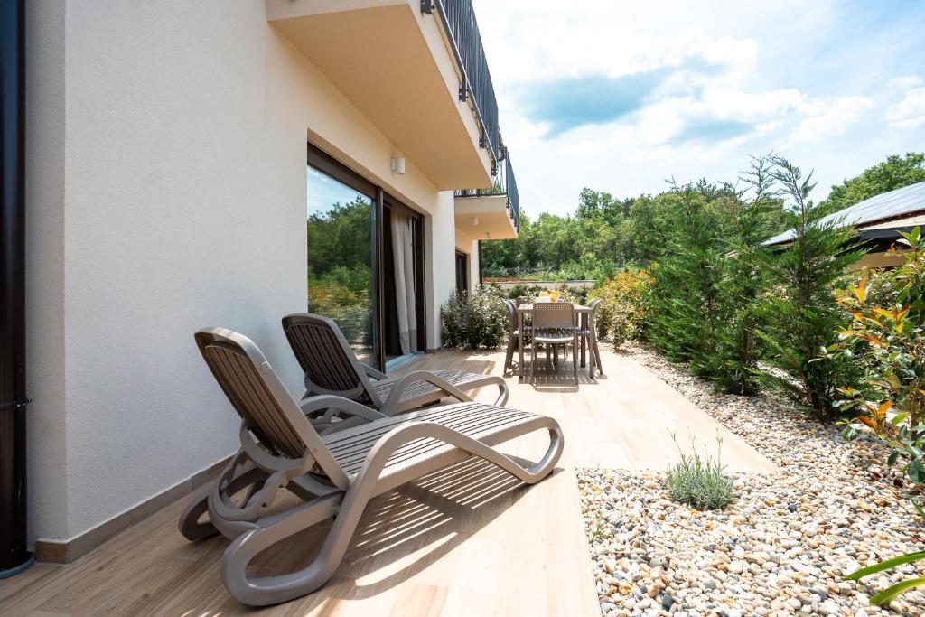 a patio with two chairs and a table on a building at VSG Resort - Relaxing Apartments, 200m from the Sea, with Pool, Sauna & Jacuzzi in Klimno