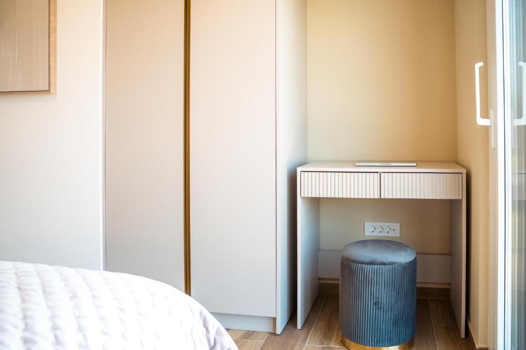 a bedroom with a table and a blue stool next to a bed at VSG Resort - Relaxing Apartments, 200m from the Sea, with Pool, Sauna & Jacuzzi in Klimno
