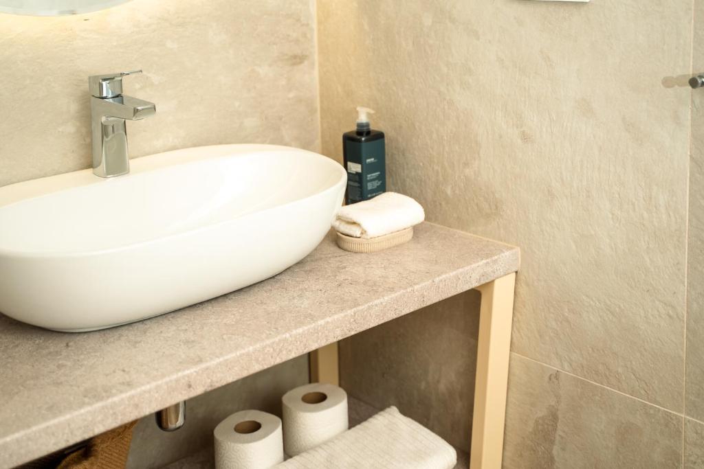 a bathroom with a white sink and some toilet paper at VSG Resort - Relaxing Apartments, 200m from the Sea, with Pool, Sauna & Jacuzzi in Klimno