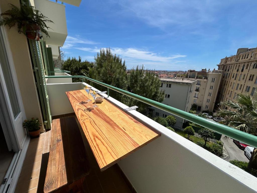 d'une table en bois sur un balcon avec vue. dans l'établissement Cosy appartement en plein centre-ville dans un halo de verdure avec vue mer, à Nice