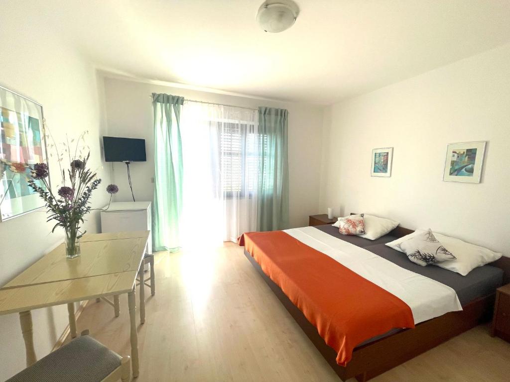 a bedroom with a bed and a desk and a window at Sobe-Sandra in Dramalj