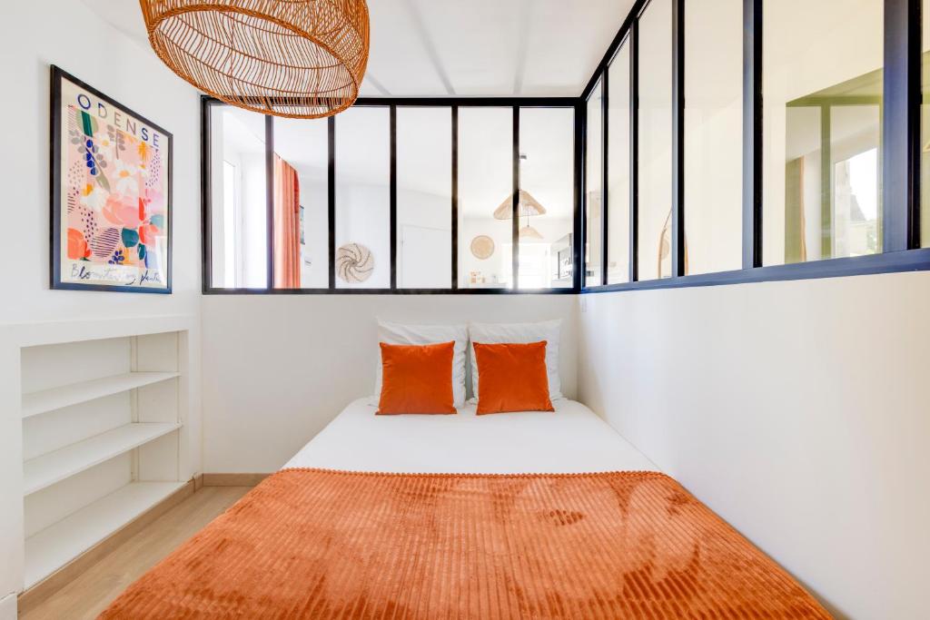 a bedroom with a bed with orange pillows and a window at Lumineux Cocon - Centre Historique - 5min Gare in Brive-la-Gaillarde