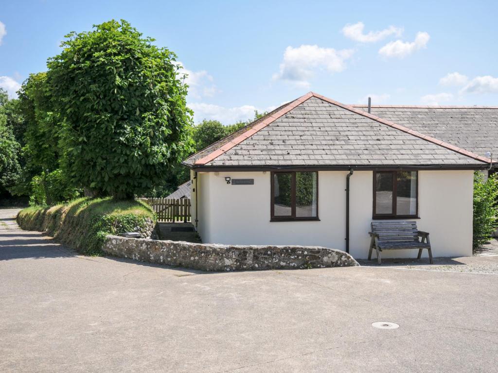 a white building with a bench in front of it at Columbine Cottage in Bude