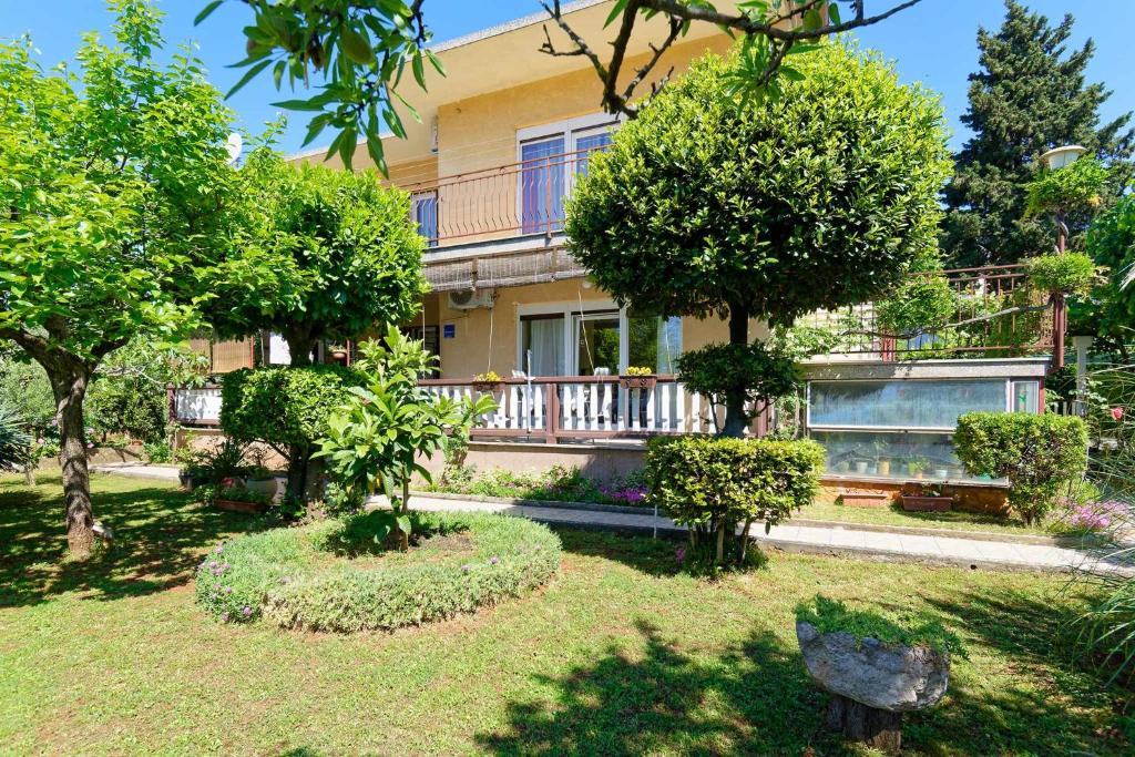 una casa con árboles frente a un patio en Apartman Darja, en Umag