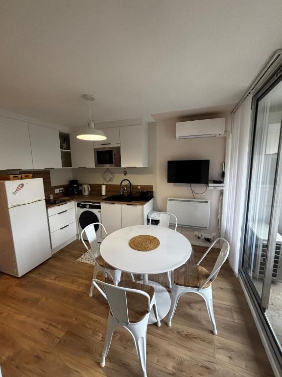une cuisine avec une table et des chaises dans une pièce dans l'établissement Superbe Appartement T2 climatisé, à Gruissan