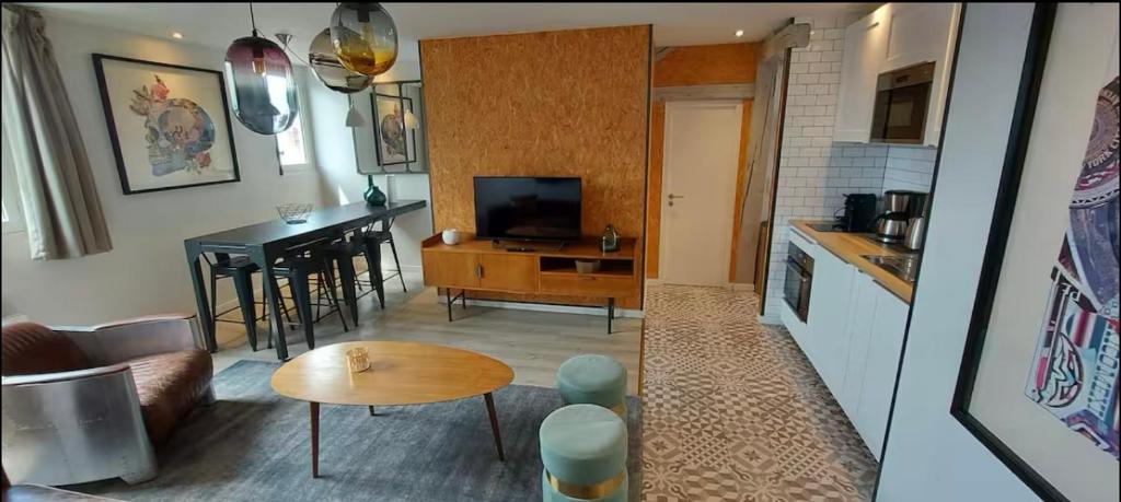 un salon avec un canapé et une table et une cuisine dans l'établissement Le 303 Appartement familial 4 personnes Deauville, à Deauville