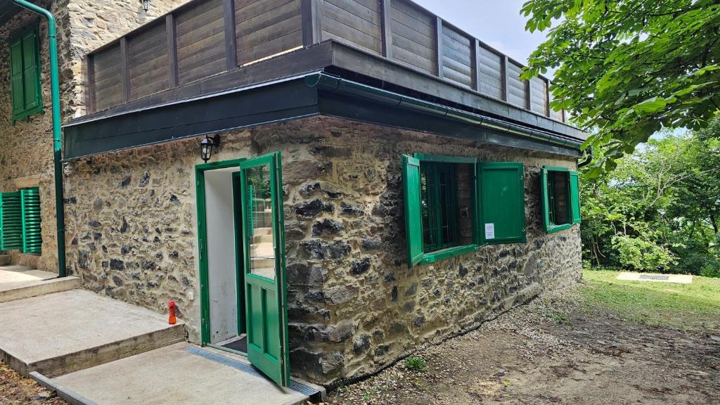 a stone building with green doors and windows at Kaán Károly Kulcsosház in Kisapáti